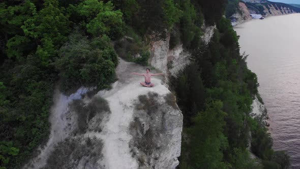 Young Shirtless Man Meditating on a Cliff at Early Morning  Looking in the Camera