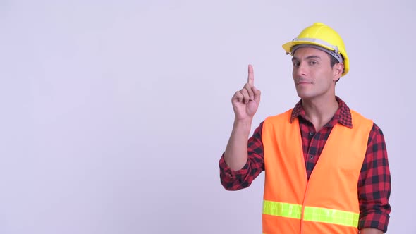 Young Happy Hispanic Man Construction Worker Thinking While Pointing Up