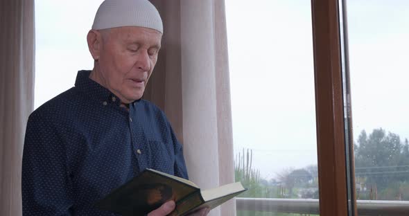 An Old Muslim Man Reading Koran at Home