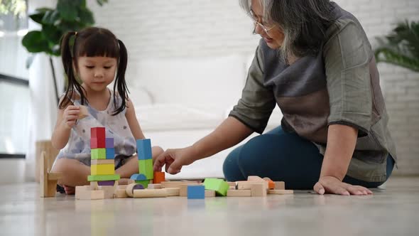 Asian girl and grandmother are sitting, imagination and paying the wooden block toy