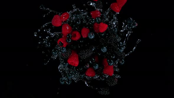 Super Slow Motion Shot of Rotating Exploded Berries Fruit with Splashing Water on Black at 1000Fps