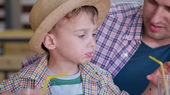 Restaurant Food, Little Boy Enjoys Fast Food and Juice Sitting at Table While Relaxing with Parents