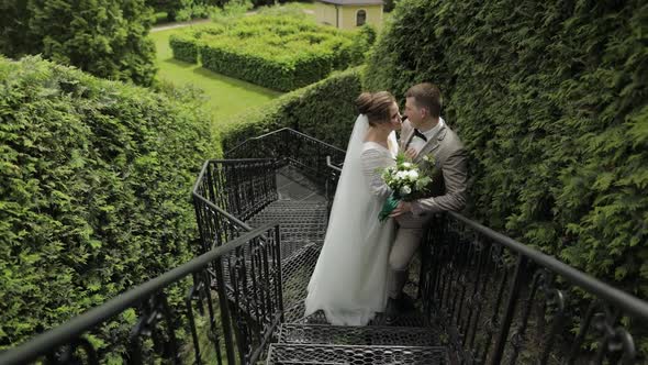 Newlyweds. Caucasian Groom with Bride Stay on Stairs in Park. Wedding Couple. Man and Woman in Love