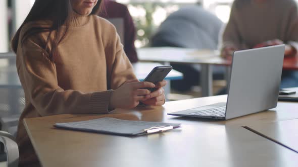 Woman Messaging on Mobile Phone at Office Desk