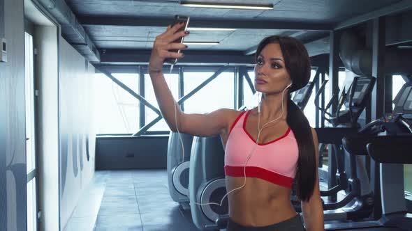 The Sweet Girl Is Making Selfie on the Background of the Gym