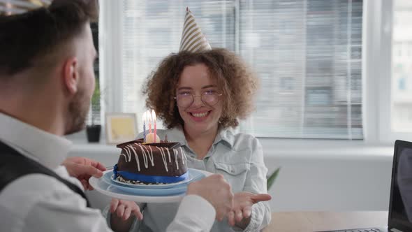 Birthday Online Smiling Girlfriend with Festive Cap on Head Makes Wish and Blows Out Candles on Cake
