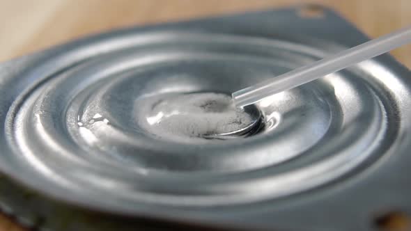 Lubricant spray is sprayed onto a metal mechanical part in slow motion. Macro