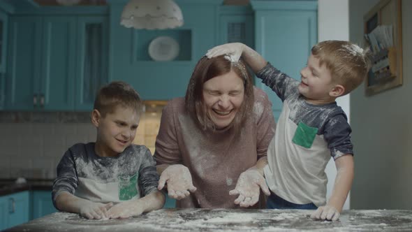 Happy family of mother and two kids having fun with flour while cooking cookies. 