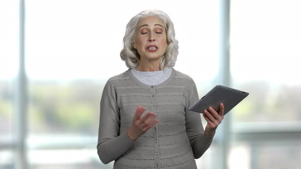 Portrait of and Old Slim Lady Holding Tablet Pc and Talking