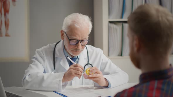 Doctor Writing Name of Patient of Medicine on Bottle with Pills