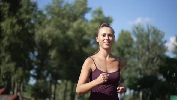 Young Beautiful Slim Woman Running in Sunlight Outdoors Smiling