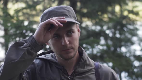 Portrait of Young Smiling Man Standing in Forest. Traveling Concept People in Nature. One Person