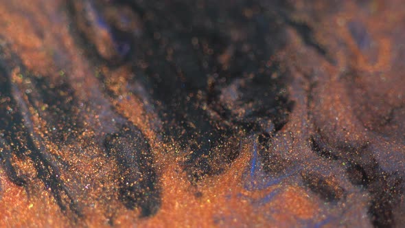 Copper and black colors oil paint with shiny particles pouring close up