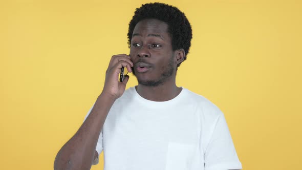 African Man Talking on Smartphone, Yellow Background