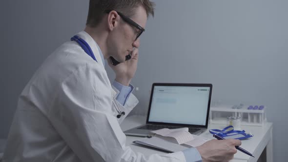 Doctor Cardiologist Examining Electrocardiogram of Patient's Heart and Consults Him By Phone in