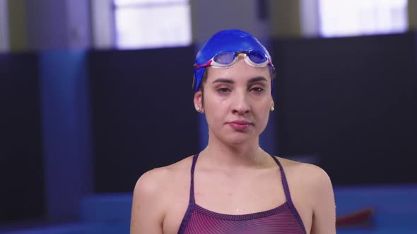 Young Woman Swimmer Puts Up Her Goggles and Looks in the Camera
