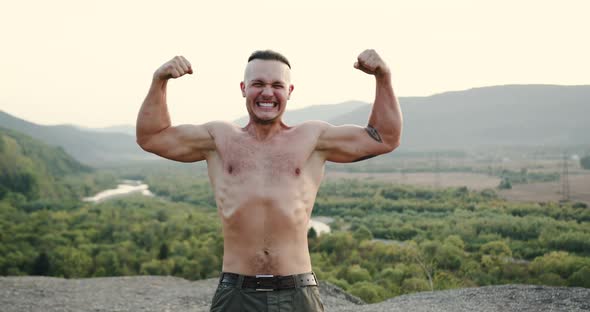 Portrait of Strong Handsome Young Athlete with Naked Torso Which Showing His Muscles on the Camera