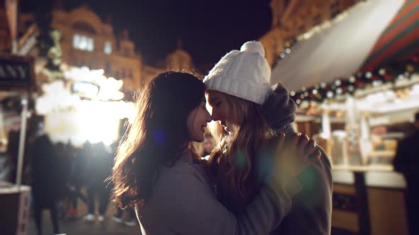 Two Girls Young Lesbian Women Embrace on the Square in the Lights of the Fair on Christmas