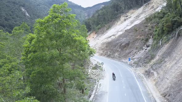 Motorcyclist Rides Along Asphalt Road Located in Ravine