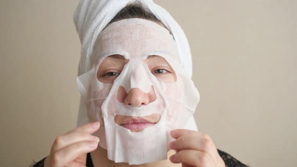 Closeup of a Woman Putting on a White Cloth Mask on Face