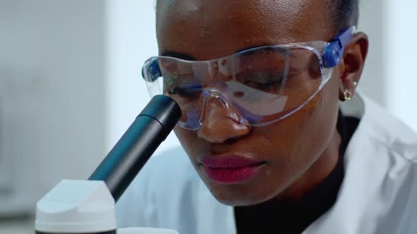 Close Up of African Woman Doctor Analysing Virus Using Microscope