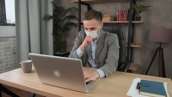 Young Businessman Coughs Into Protective Face Mask Working in the Office. Caucasian Man with Acute