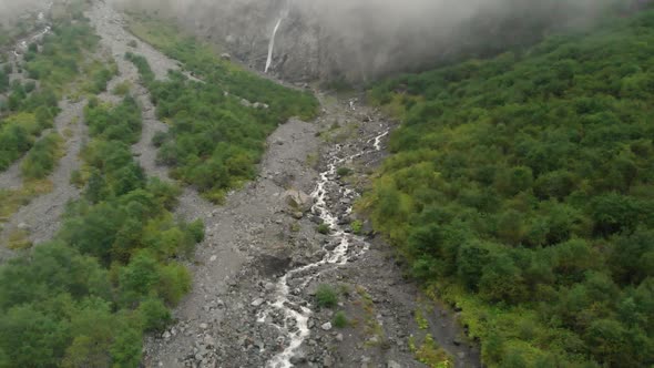 Aerial View Waterfall Flows Down From the Mountains Forming a Stream and Fog