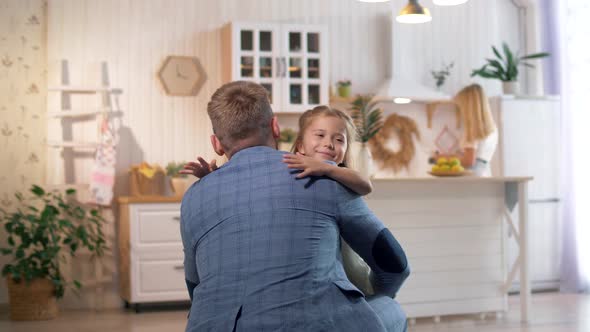 Beautiful young girl greets dad from work, smiles and hugs him. Staging in a photo studio