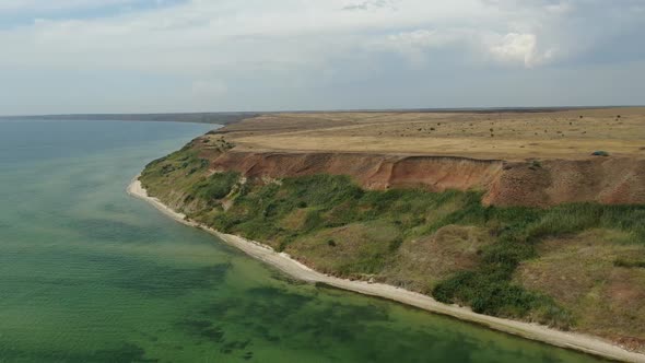 Aerial View on the Massive Hills Along the Seashore with a Car Driving on Top