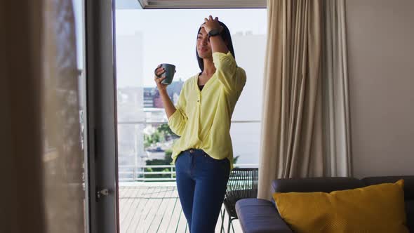 Mixed race gender fluid person drinking cup of coffee on roof terrace