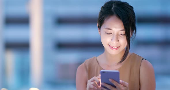 Asian woman check on cellphone in city at night