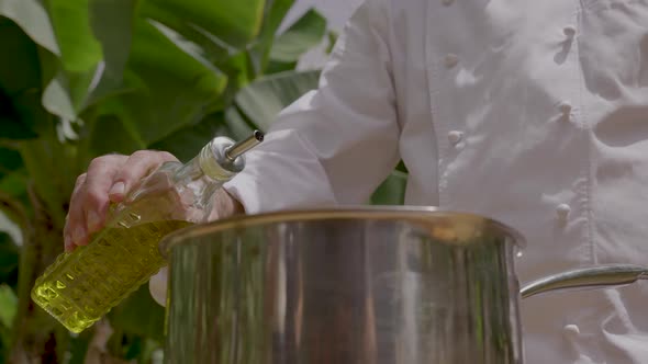 Chef pouring extra virgin olive oil on a metal pan