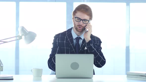 Redhead Businessman Talking on Phone, Attending Call at Work