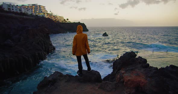 Girl in Orange Jacket Enjoying the Sunset View of Acantilado De Los Gigantes Natural Pool or Piscina