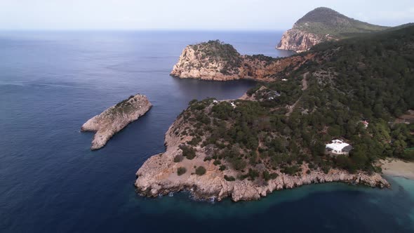 Beautiful Nature scape of Ibiza Cliffs and Ocean, Trees Filling Mountain Side - Sliding Aerial Shot