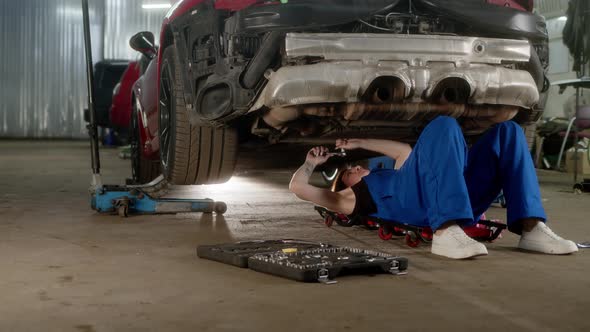 Woman Car Service Worker Lies Under Car and Repairs It