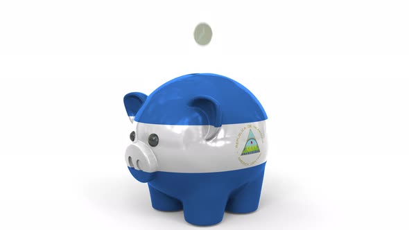Coins Fall Into Piggy Bank Painted with Flag of Nicaragua alt