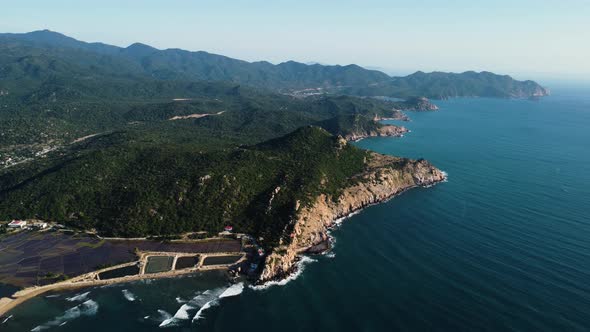 Mountain landscape with rocky seaside cliffs and small sandy beach in Vietnam. High altitude aerial