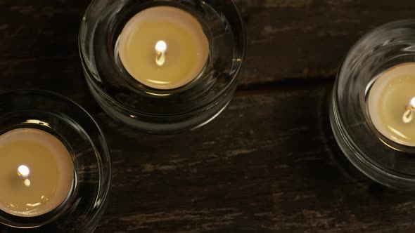 Tea candles with flaming wicks on a wooden background 