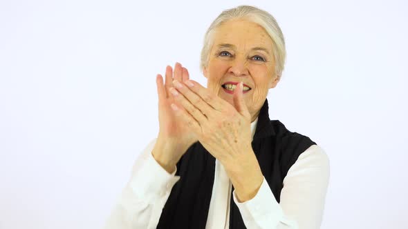 An Elderly Woman Applauds and Smiles at The Camera