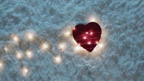 Hands Wrap Red Heart With Fairy Lights in Magic Atmosphere