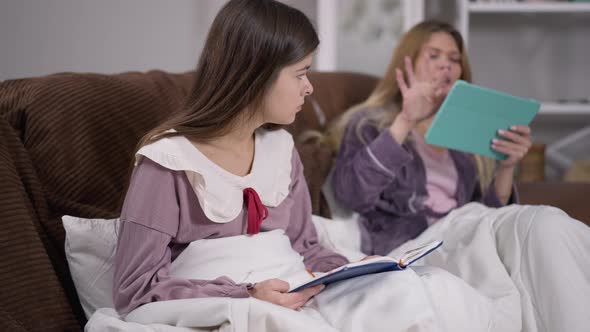 Portrait of Concentrated Absorbed Woman Studying Indoors As Roommate Messaging Online on Tablet