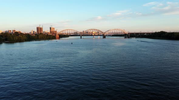 Establishing Aerial View Shot of Summer Down Kyiv Cityscape with Railway Bridge Over the River