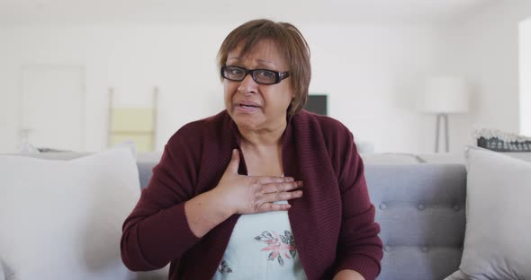 Sad, sick african american senior woman making video call at home