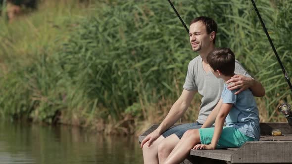 Smiling Boy and His Father Fishing on Pier