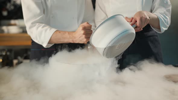 Close-up of a professional kitchen: liquid nitrogen is added during the cooking of a molecular dish