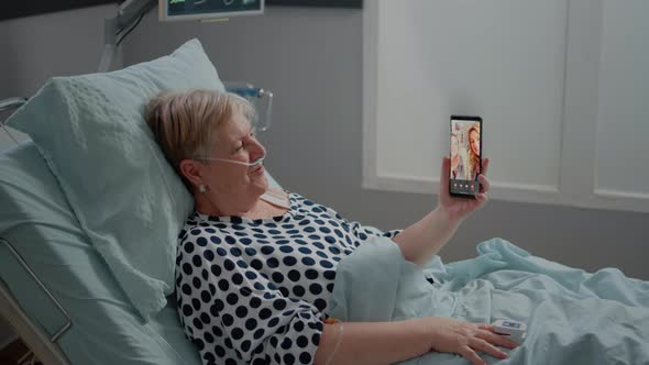 Senior Patient Talking to Family on Video Call in Hospital Ward Bed