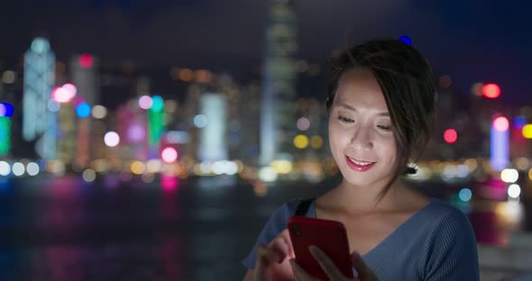 Woman use of smart phone in city at night