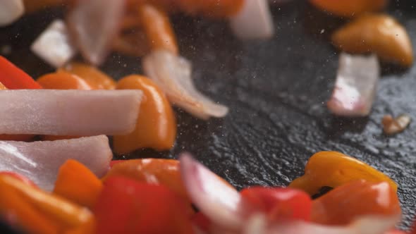 Stir frying onion and orange and red bell pepper. Slow Motion.