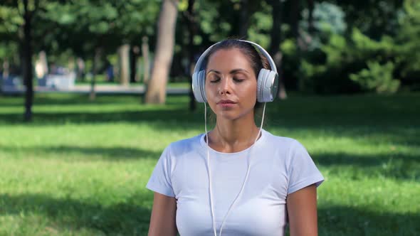 Girl Doing Yoga in the Park and Listening Music on Headphones, Sunny Day